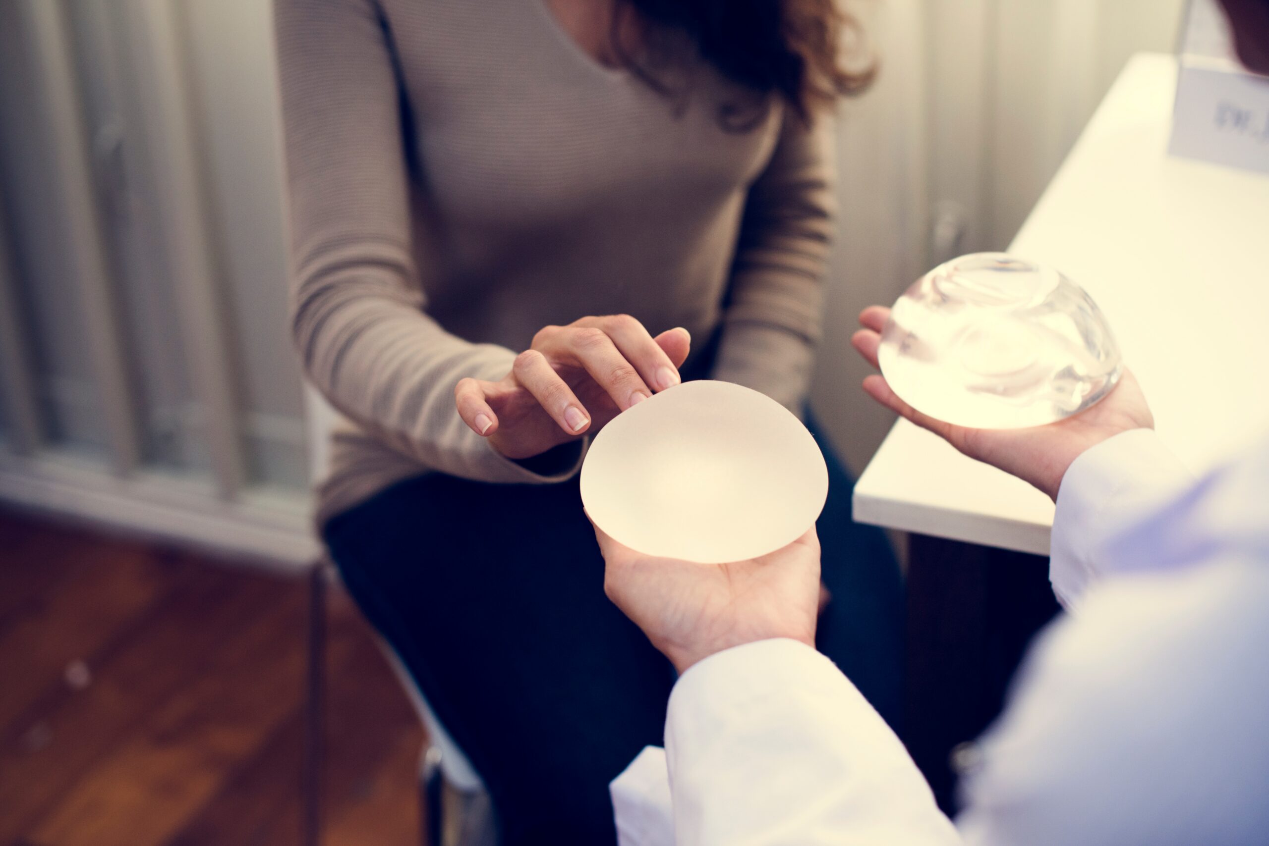 Surgeon showing breast implant sizers to a seated patient