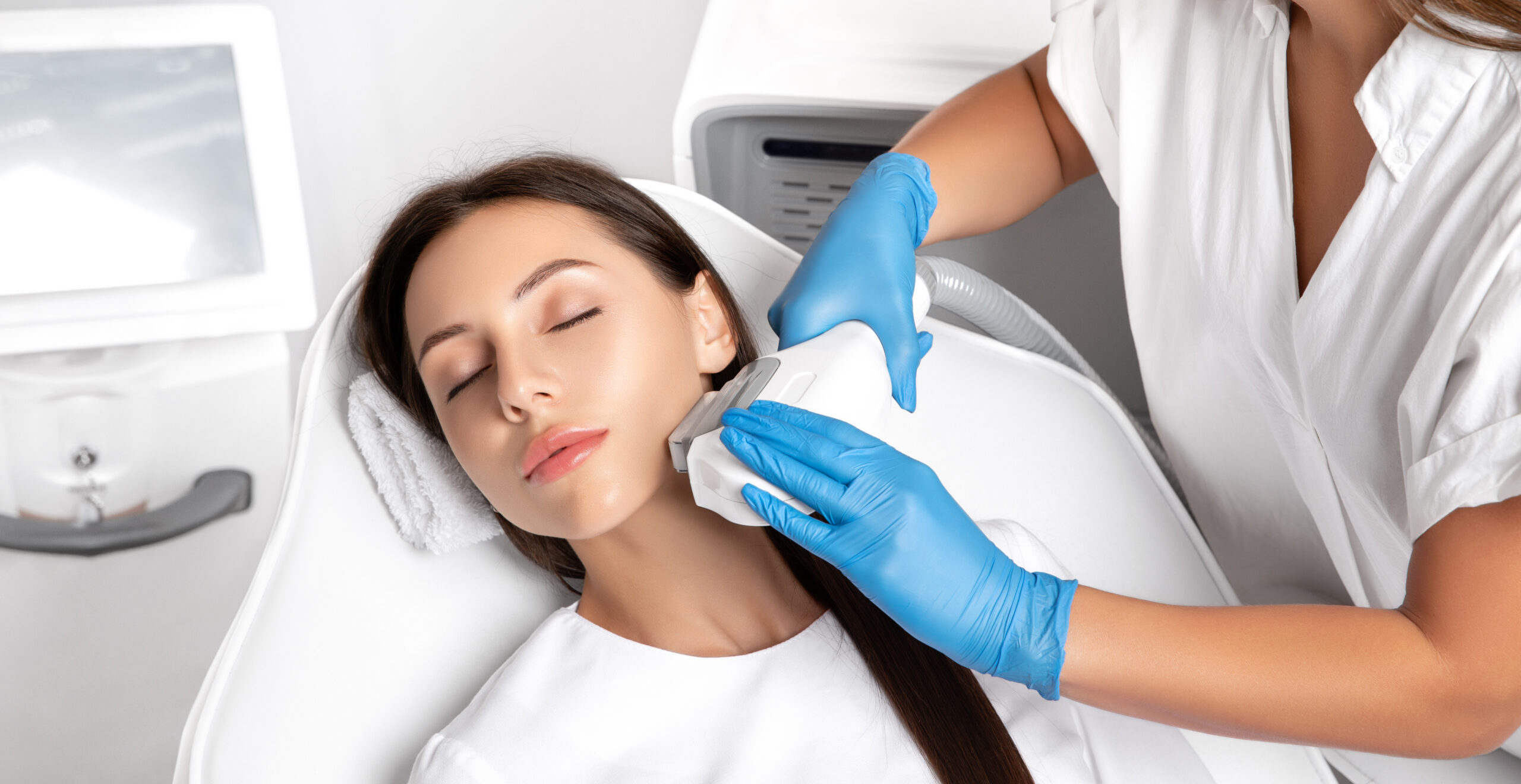 Technician applying a laser device to a woman's neck and jawline