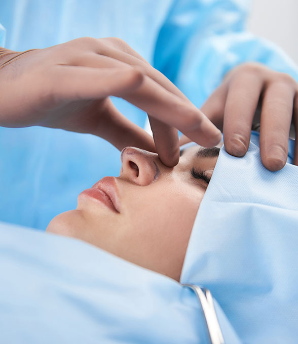 Gloved hands examining a patient's nose before a procedure