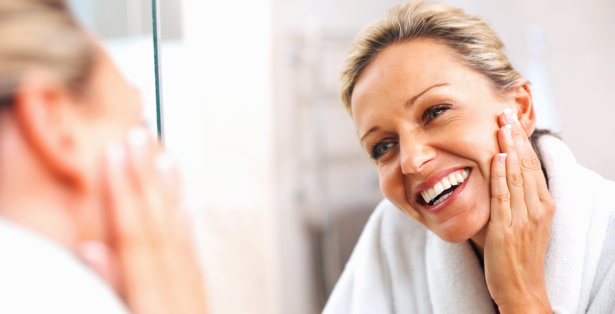 Happy mature woman admiring herself in the mirror Neck Lift in Bucks County, PA and Hunterdon County, NJ
