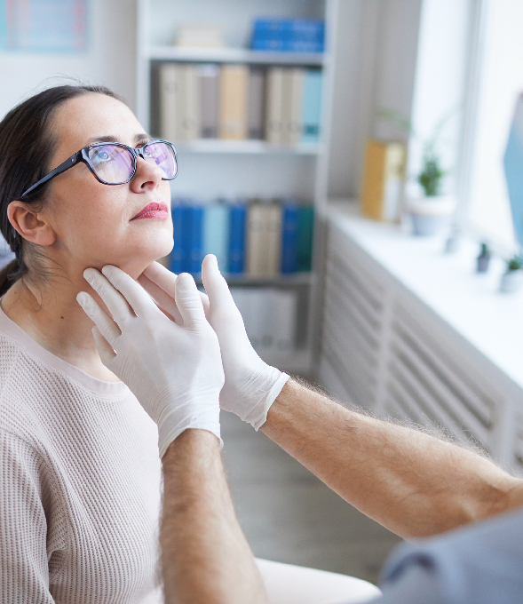 Gloved hands examining a woman's neck during a consultation