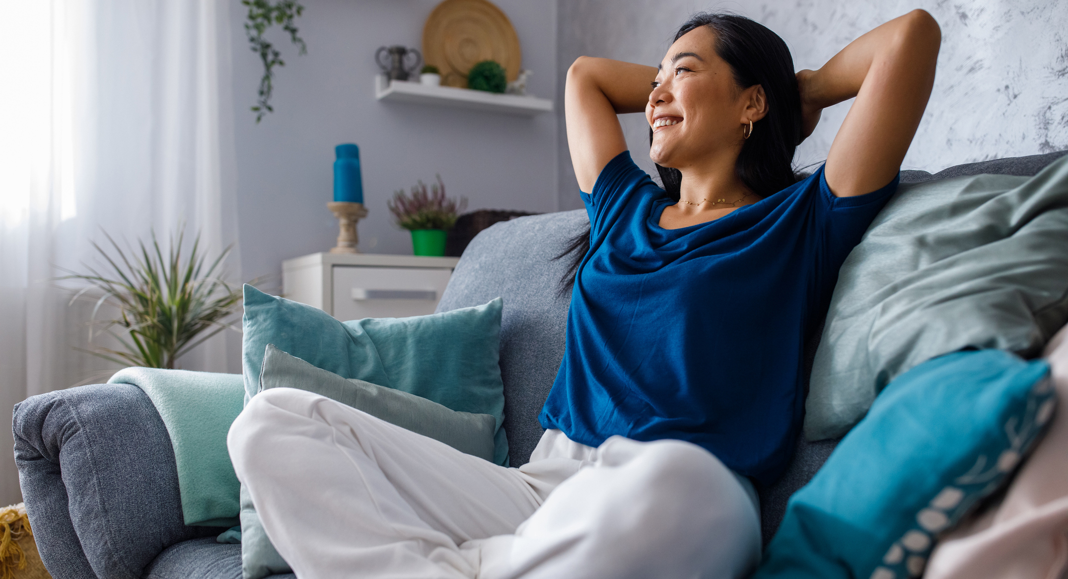 Copy space shot of young woman lounging on sofa with hands behind head and daydreaming