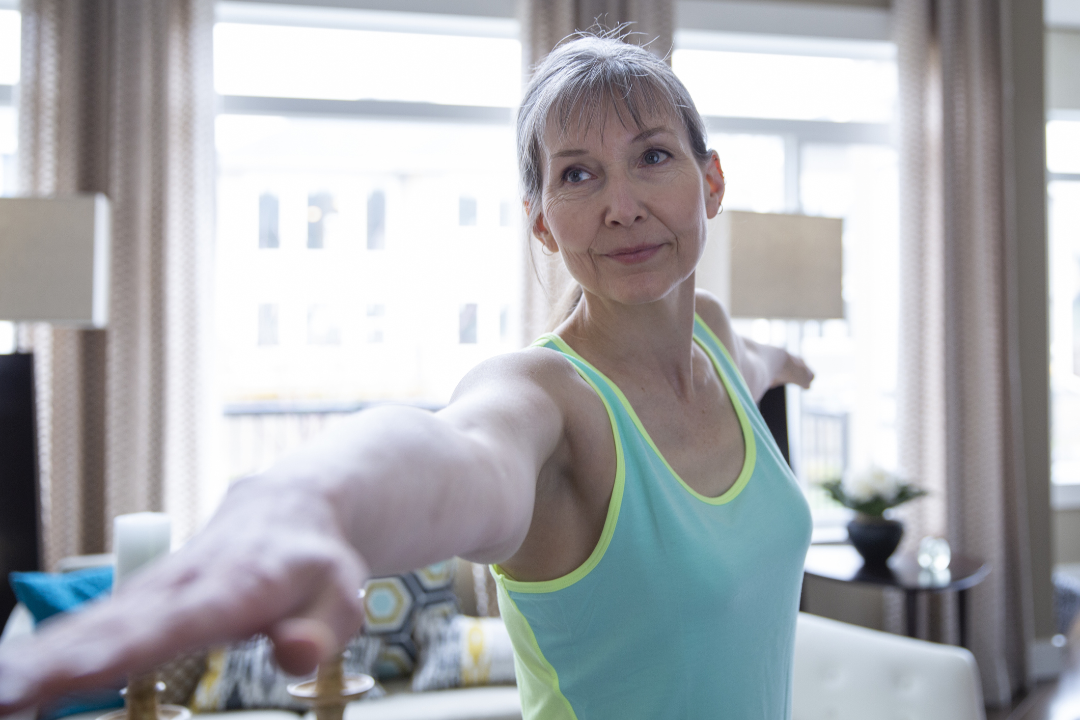 Woman practicing yoga in living room at home Arm Lift (Brachioplasty) in Bucks County, PA & Hunterdon County, NJ