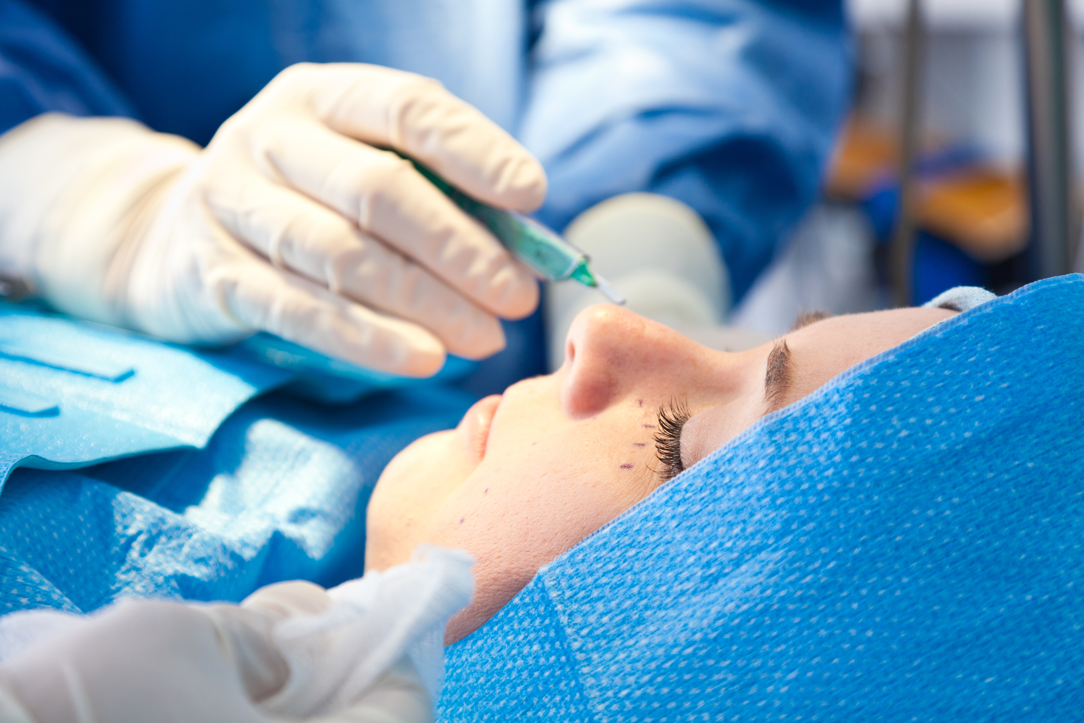 Surgeon injecting near a patient's eyebrow during a procedure