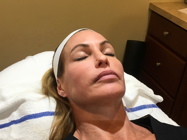 Woman reclining on a treatment table with a headband, eyes closed