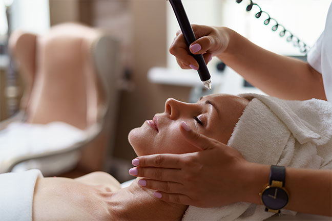 Esthetician performing a facial treatment on a reclining patient